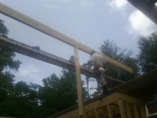 Carpenter setting a ridge beam over a new addition frame — Ice Dam Removal by Roofing Brothers in Gilberton