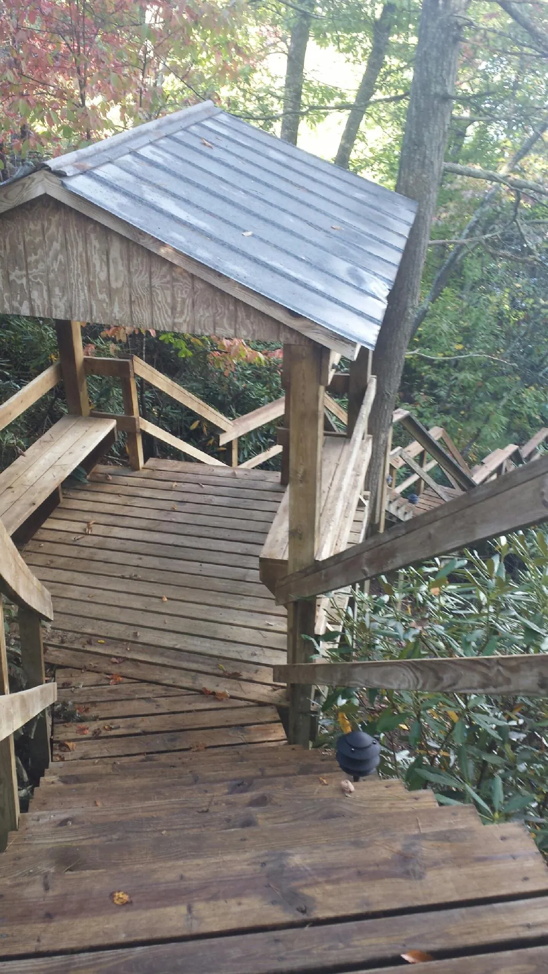 Metal roofed shelter over wooden steps on a wooded walkway — Skylight Repair & Installation work by our crew in Gilberton