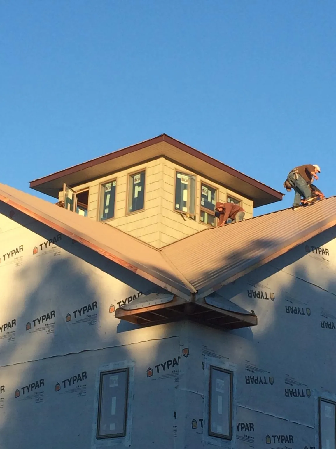 Roofers working around a rooftop cupola on a new metal roof at sunset — Roof Waterproofing in Gilberton by Roofing Brothers
